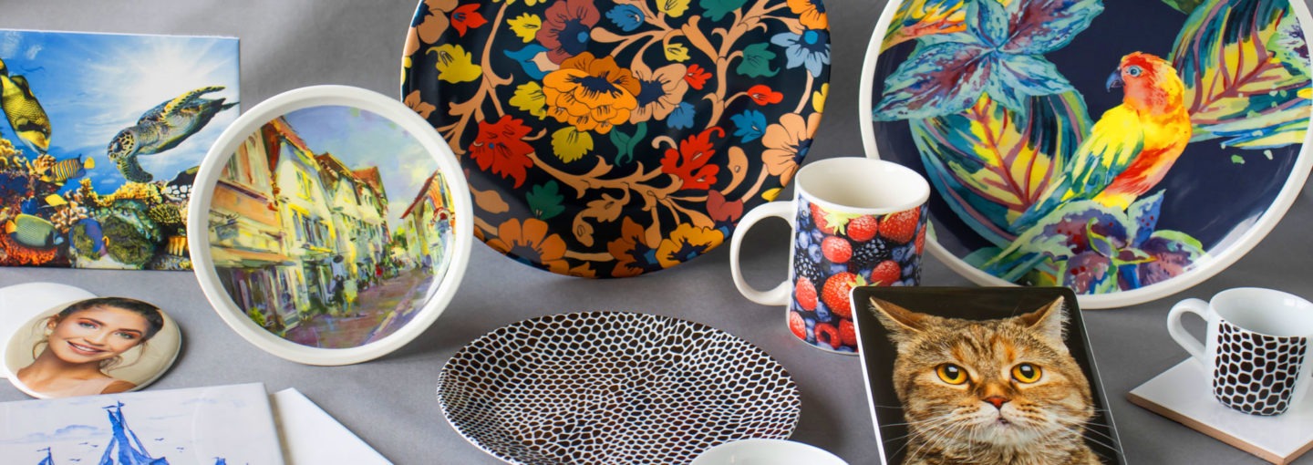 Das Bild zeigt eine Auswahl keramischer Endprodukte aus Porzellan, Keramik, emailliertem Metall und Glas. Die Dekore werden mit Hilfe keramischer Abziehbilder auf die Produkte gebrannt.